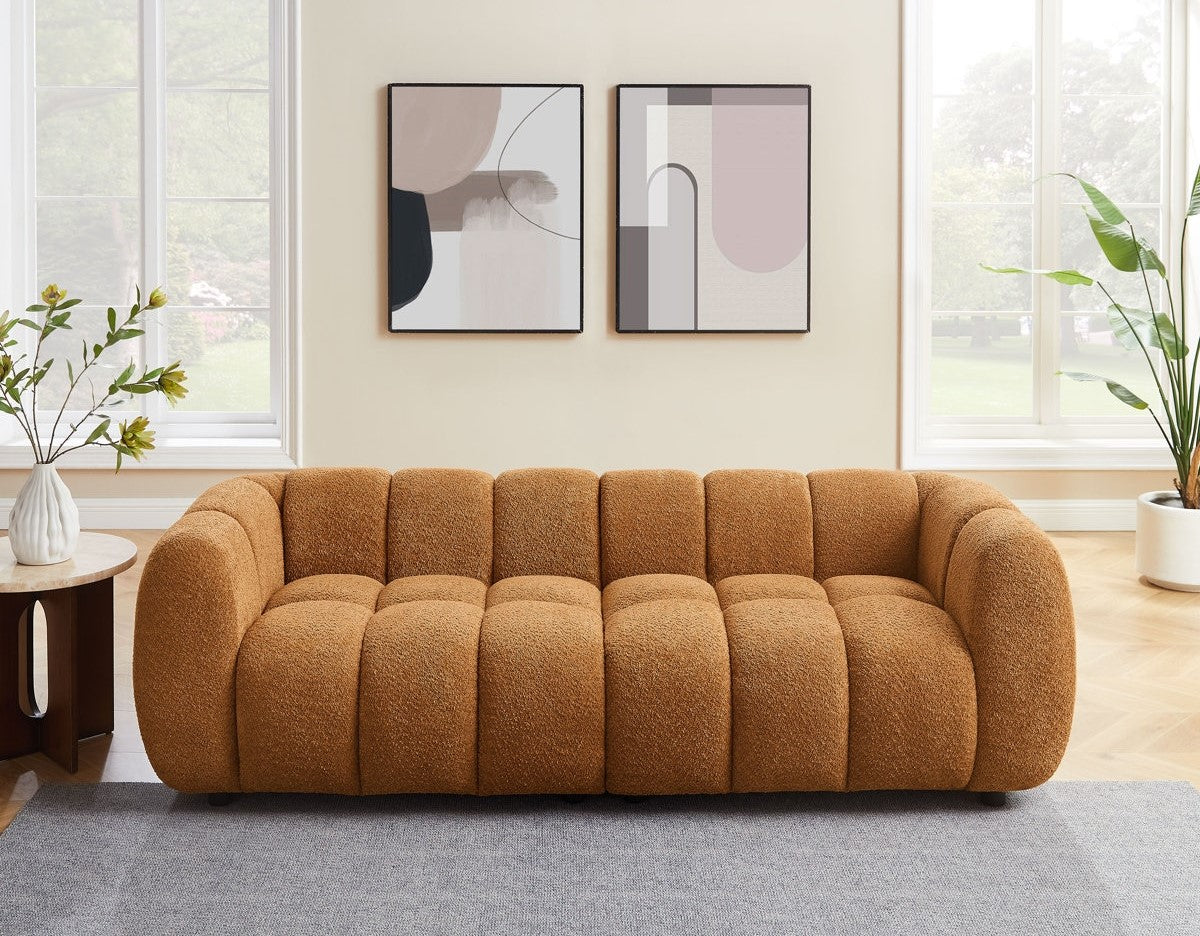 Brown sofa in a living room with abstract art on the wall and plants.