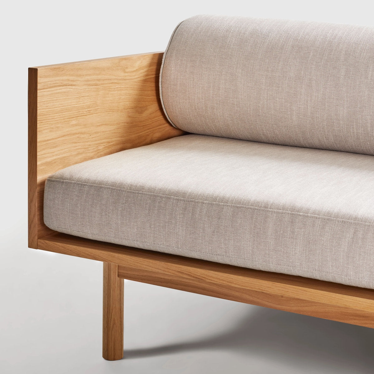 Sofa with wooden frame and beige cushions on a light gray background