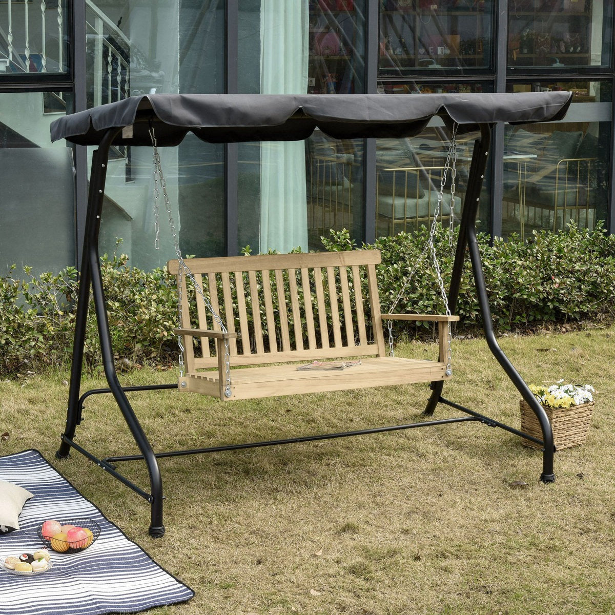 Wooden swing with black metal frame on grass, outdoor setting