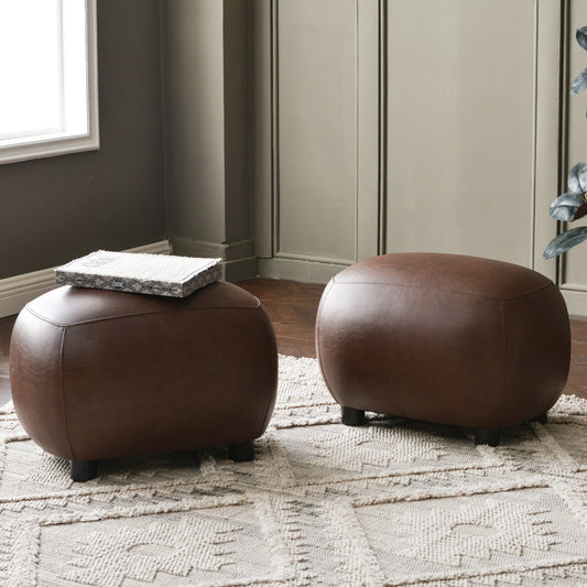 Two brown leather ottomans in a room with a textured rug and neutral walls.