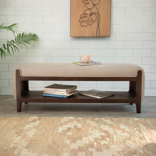 Beige upholstered bench with wooden shelf against a white tiled wall.