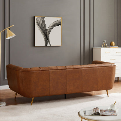 Brown leather sofa in a living room with a gray wall, lamp, and framed artwork.