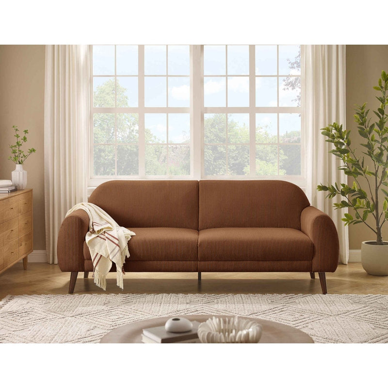 Brown sofa in a living room with large windows and plants
