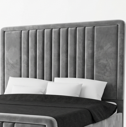 Gray upholstered bed with white pillows and black bedding on a bed.