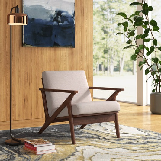 Wooden armchair with beige cushion in a room with a painting, lamp, and plant.