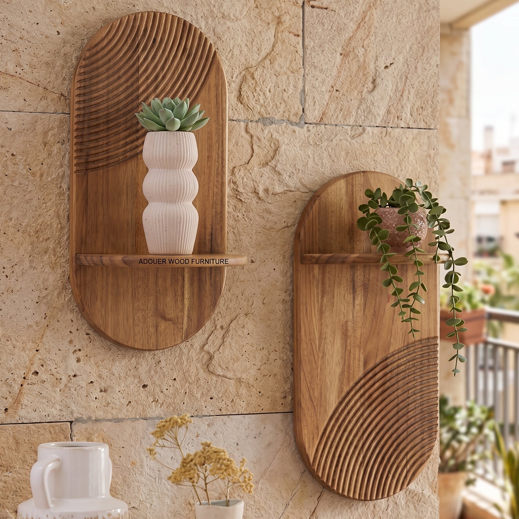 Two oval wooden wall shelves with carved wave patterns, mounted on a beige stone wall. One shelf holds a small potted succulent in a ribbed white vase, and the other holds a trailing green plant in a pink pot.