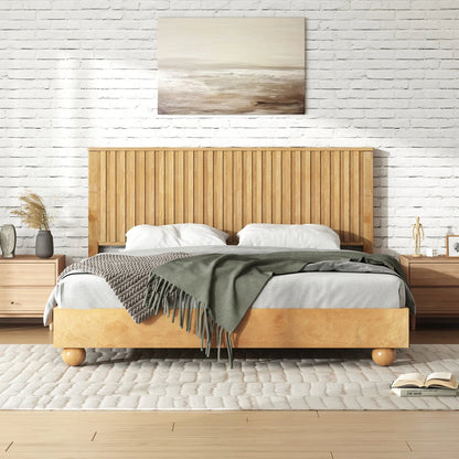 Wooden bed with a green blanket in a room with a white brick wall and wooden floors.