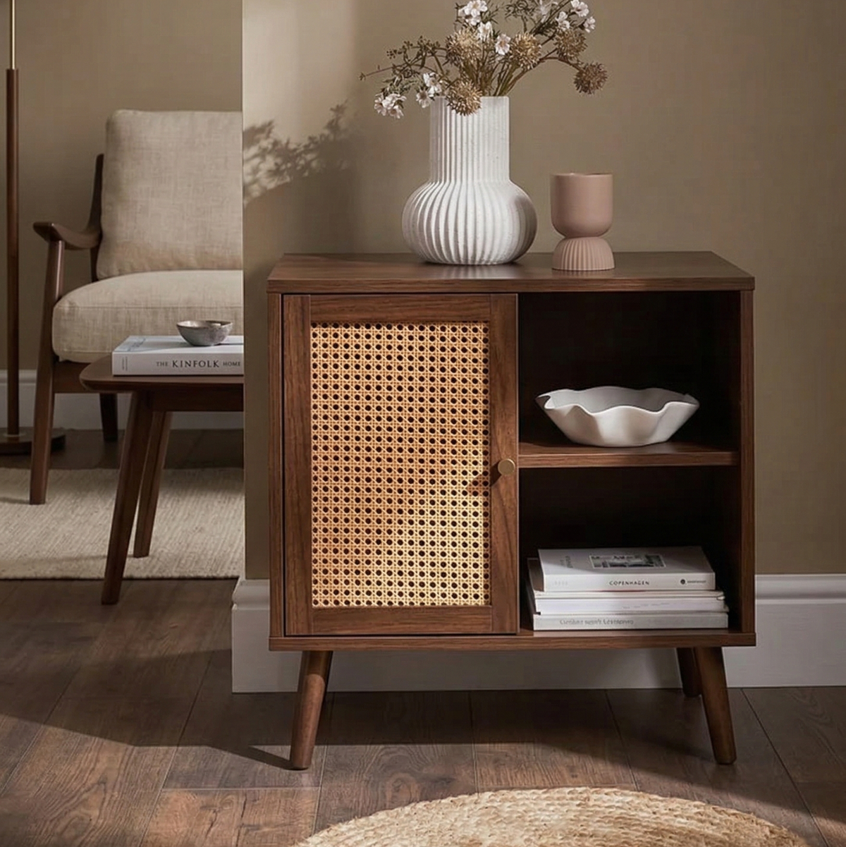 Wooden cabinet with wicker door in a room setting with books and decor items.
