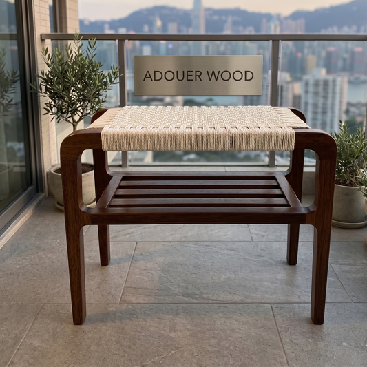Wooden stool with woven seat on a balcony with 'ADOUER WOOD' sign in the background