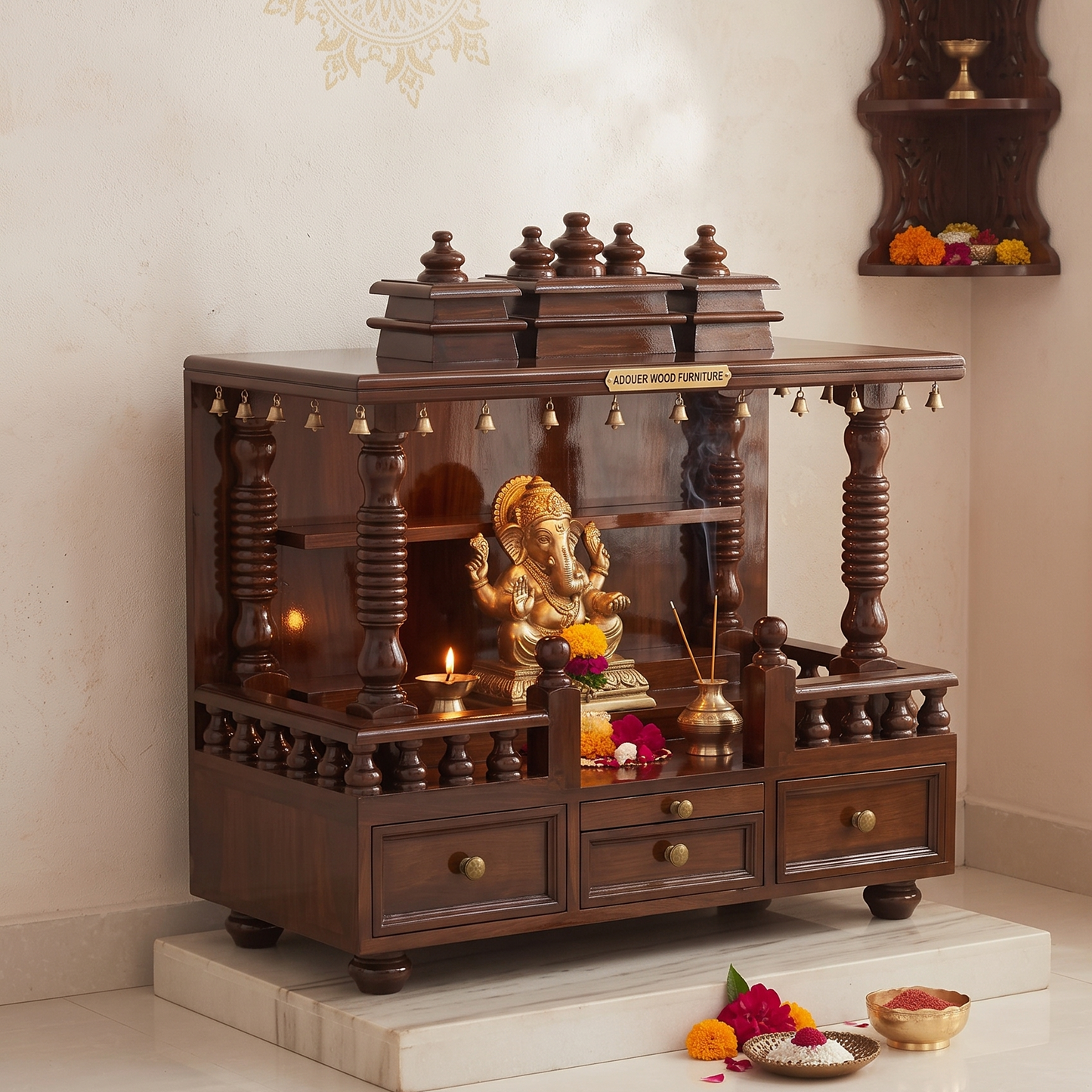 A dark brown wooden Hindu deity stand with a brass Ganesh statue, decorated with flowers and small hanging bells, set against a cream-colored wall.