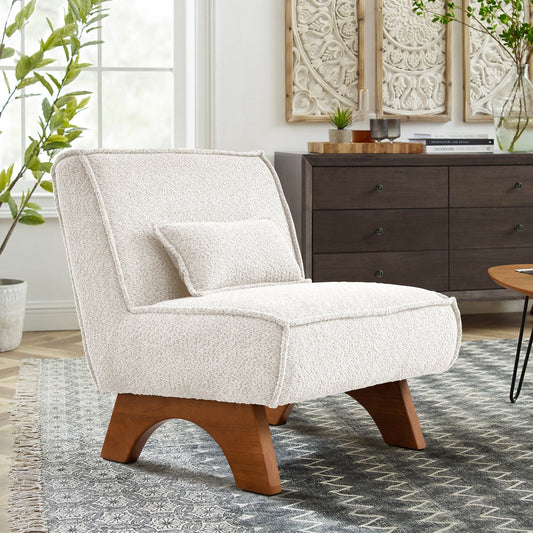 White upholstered armchair with wooden legs in a room with a dresser and plants.