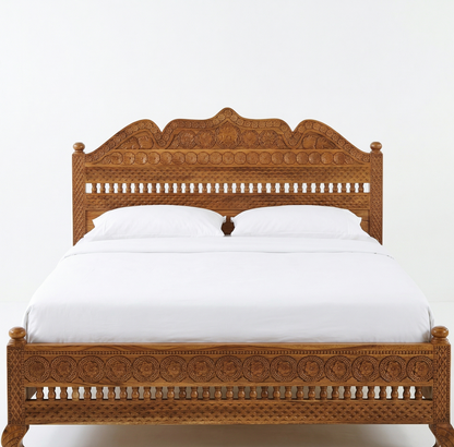 Wooden bed with intricate carvings on a white background