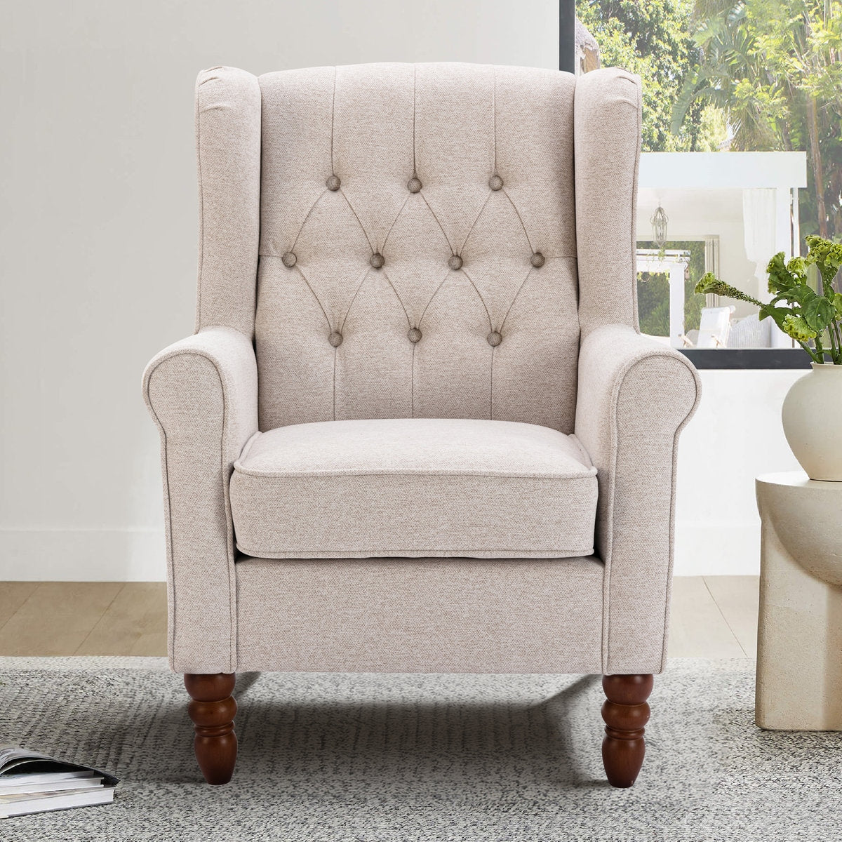 Beige armchair with tufted backrest in a room with a plant and window.