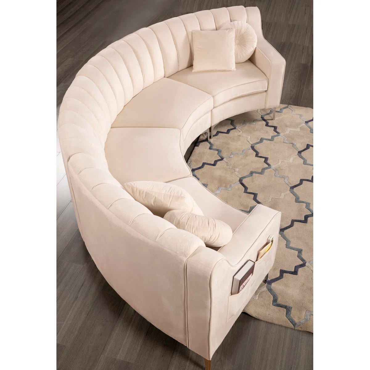Beige curved sectional sofa on a wooden floor with a patterned rug.