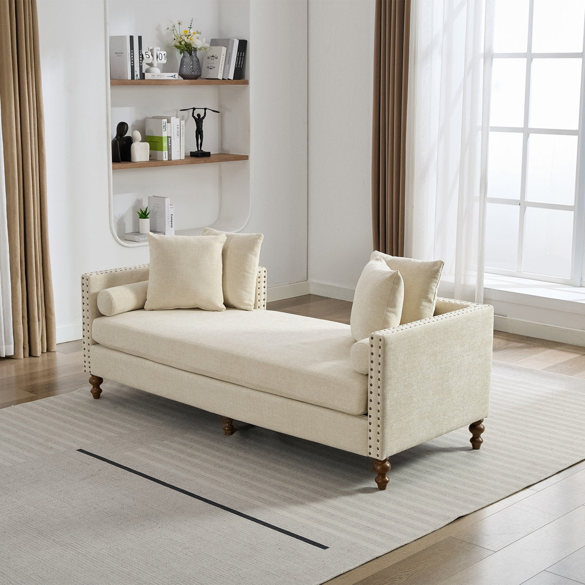 Beige daybed with pillows in a room with a window and shelves.