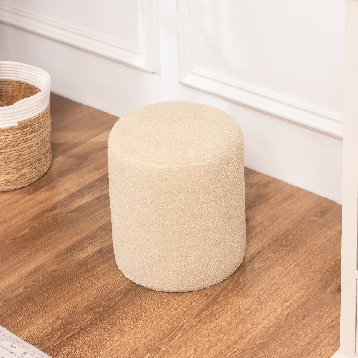 Beige pouf on a wooden floor next to a woven basket