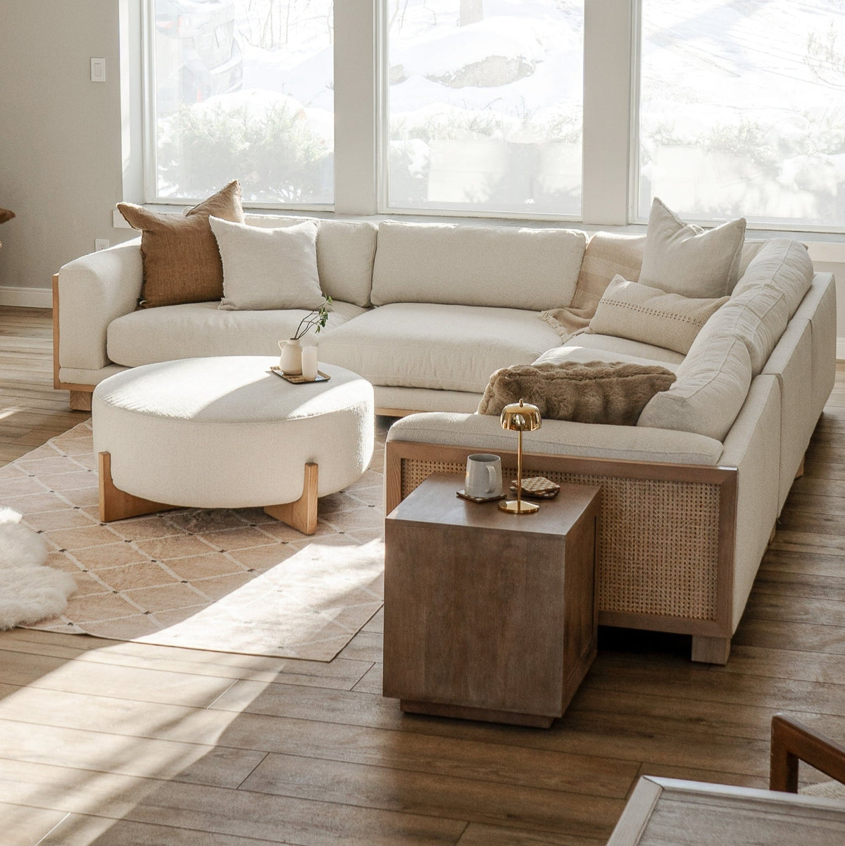 Beige sectional sofa with matching ottoman in a bright living room.