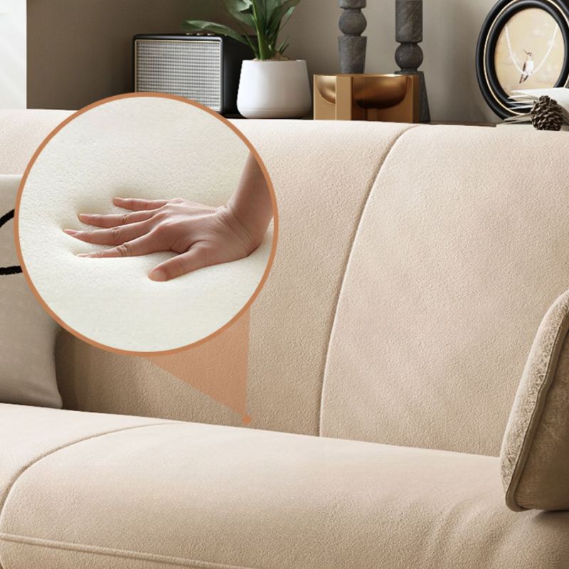 Beige sofa with a close-up of a hand on a cushion, surrounded by home decor items.