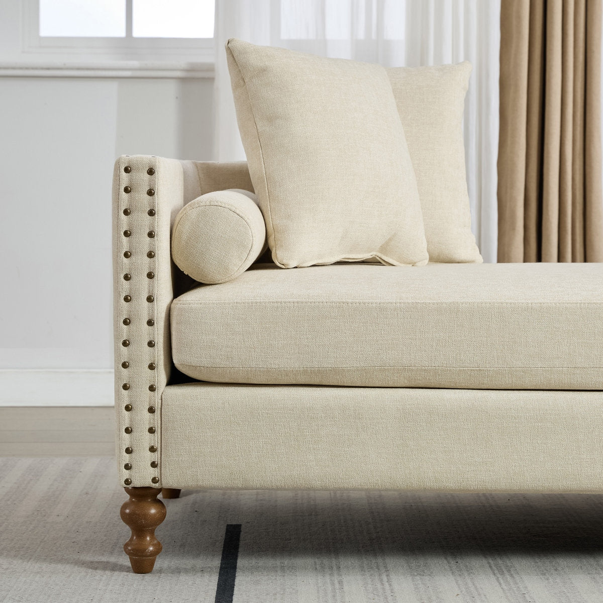 Beige sofa with decorative pillows in a room with white walls and curtains.