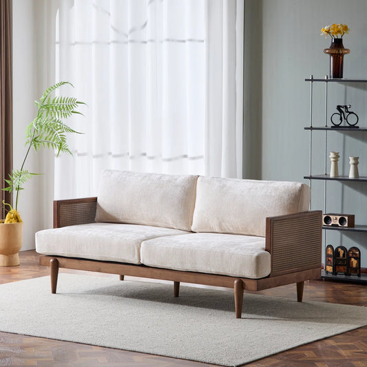 Beige sofa with wooden frame in a room with large windows and decorative items.