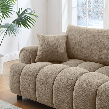 Beige textured sofa with a pillow in a bright room with a window and plant.