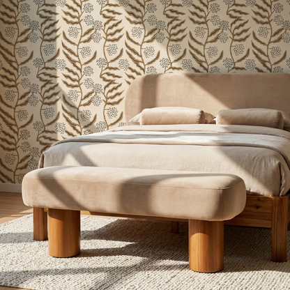 Beige upholstered bench in front of a bed with floral wallpaper