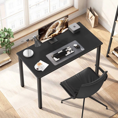 Black desk with office items in a bright room.