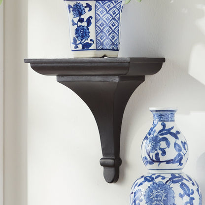 Black wall bracket with blue and white floral vases on a white wall
