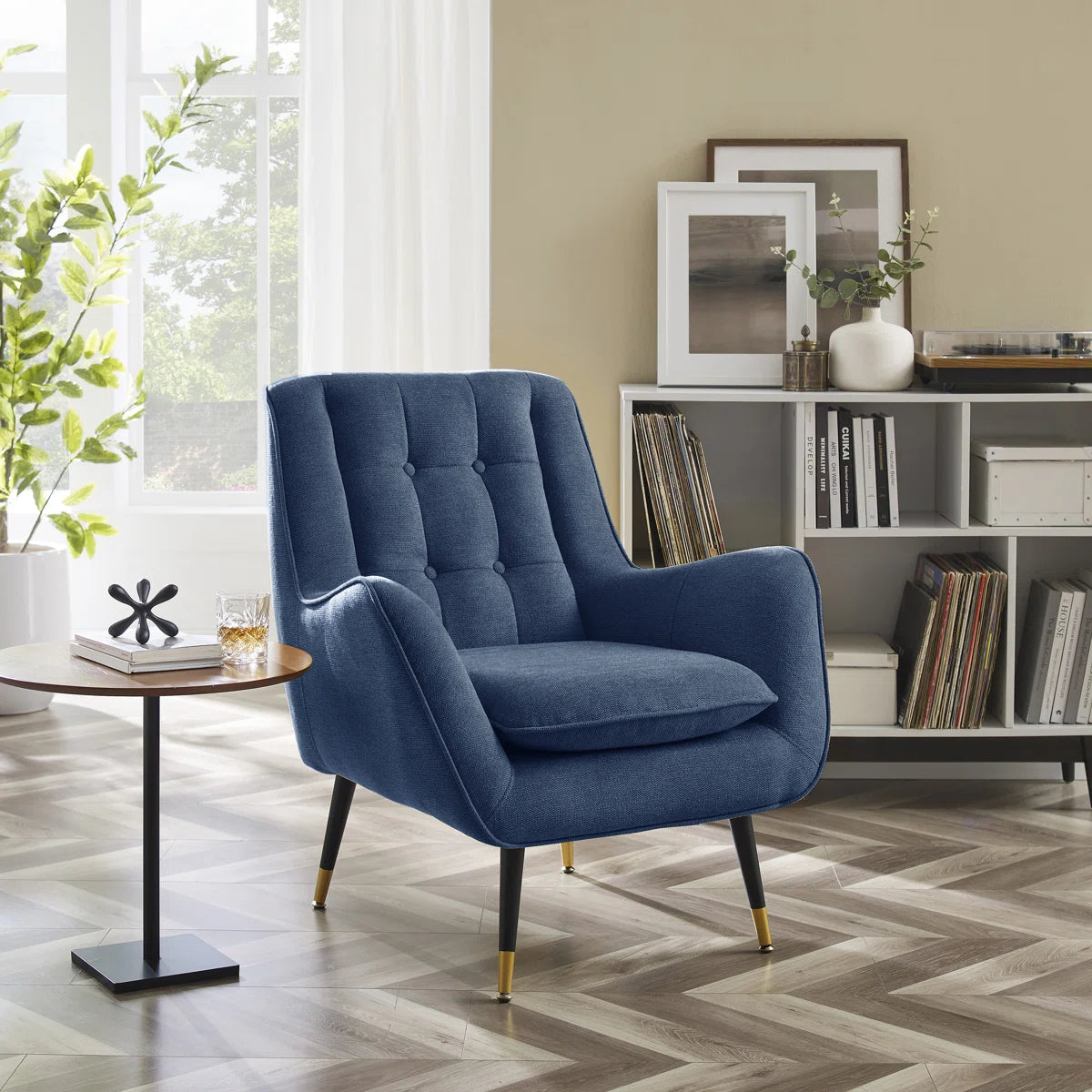 Blue armchair in a living room with a bookshelf and table.