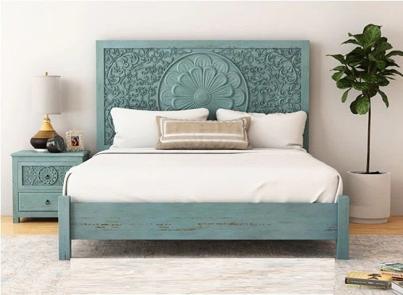 Blue wooden bed with intricate carvings in a bedroom setting