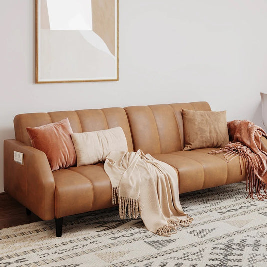 Brown leather sofa with decorative pillows and a blanket in a living room setting.