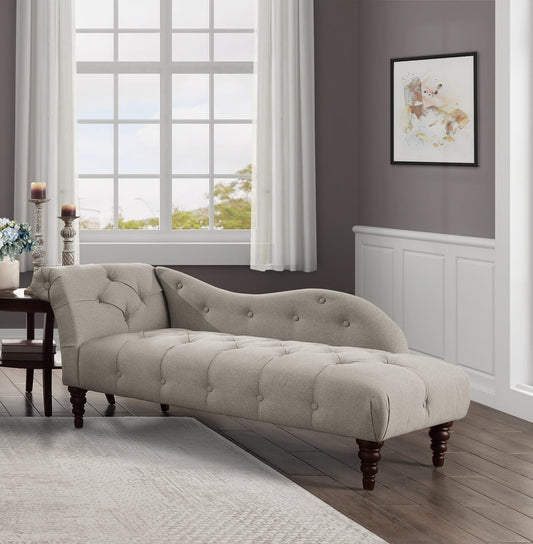 Beige chaise lounge in a living room setting with a large window and framed artwork on the wall.