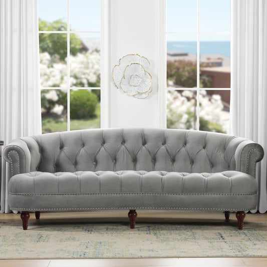Gray tufted sofa in a room with large windows and white curtains.