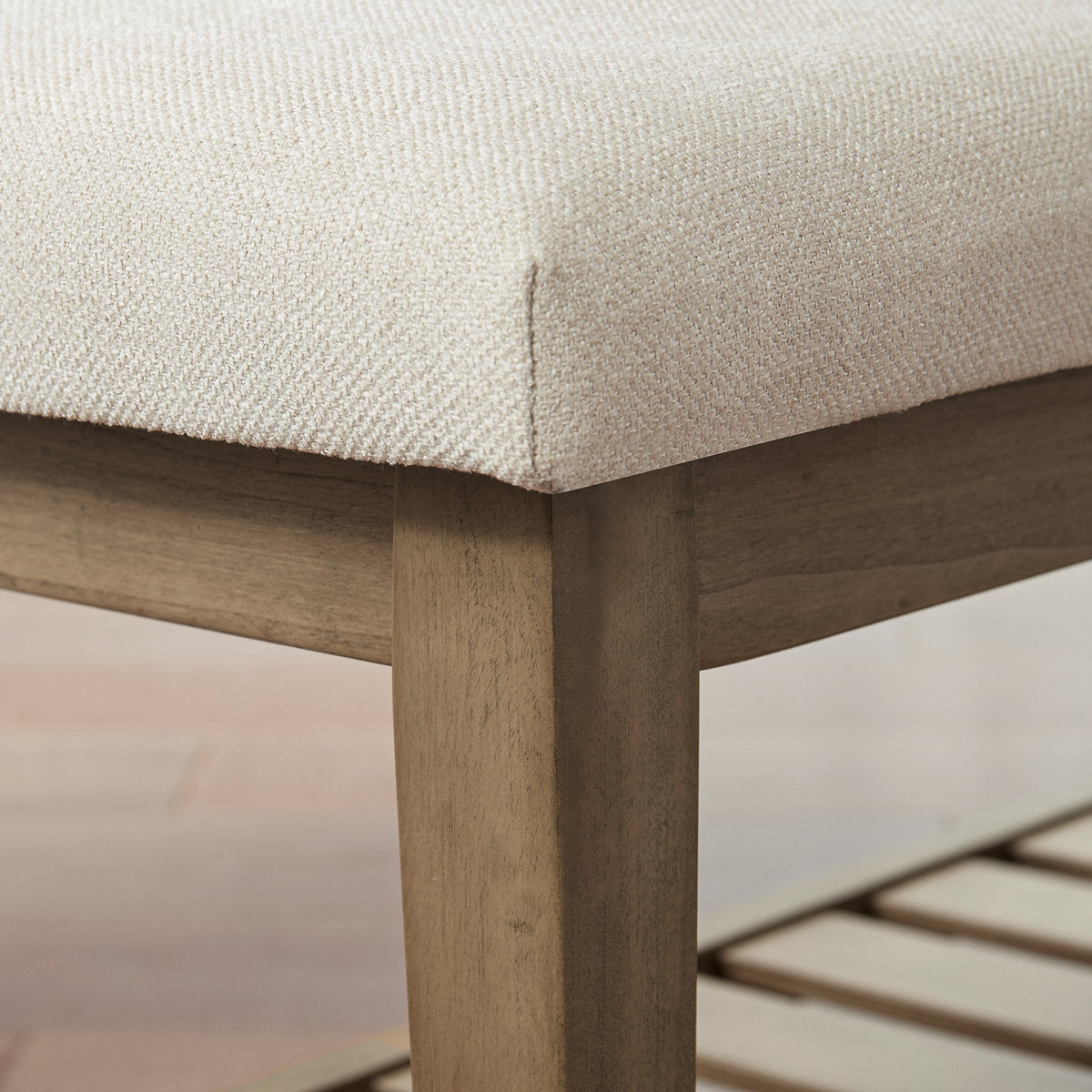Close-up of a wooden chair with a beige cushioned seat.