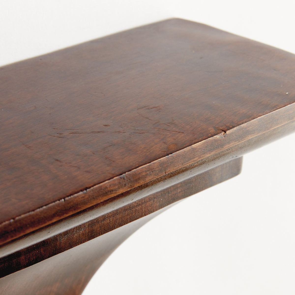 Close-up of a wooden surface with a white base on a white background