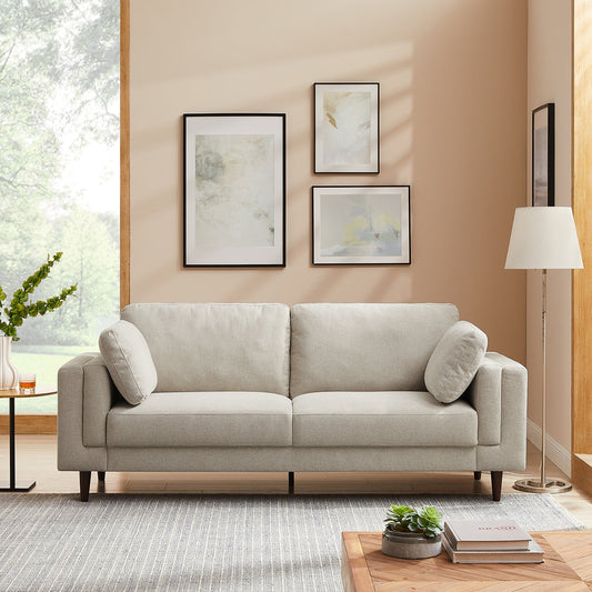 Gray sofa in a living room with abstract art on the wall and a lamp.