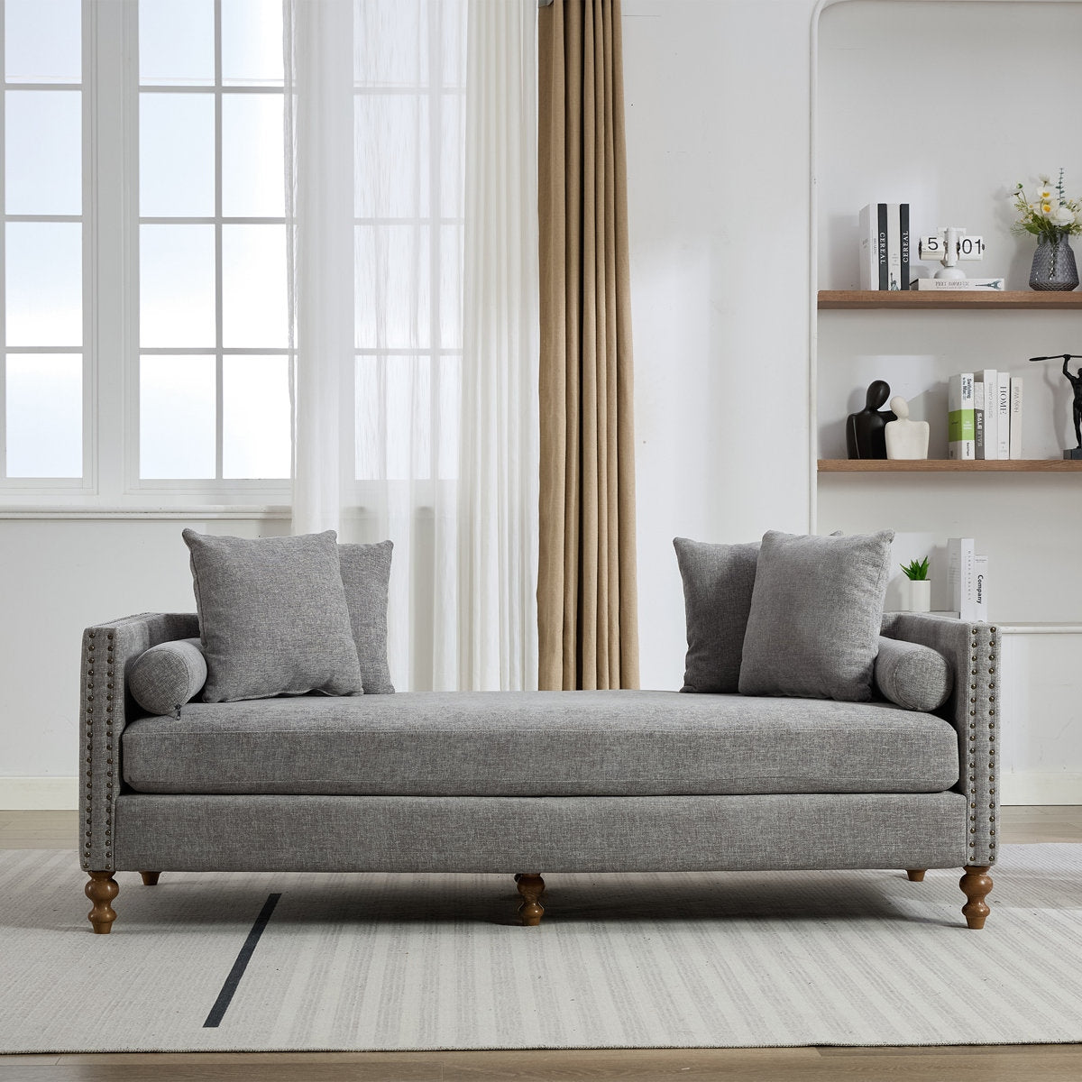 Gray sofa in a living room with a window and bookshelf in the background