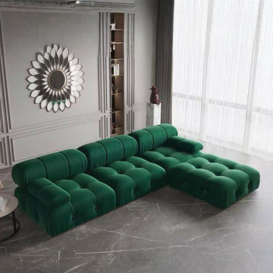Green sectional sofa in a modern living room with a decorative mirror and bookshelf.