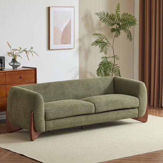 Green sofa in a room with a wooden cabinet, plant, and abstract art on the wall.