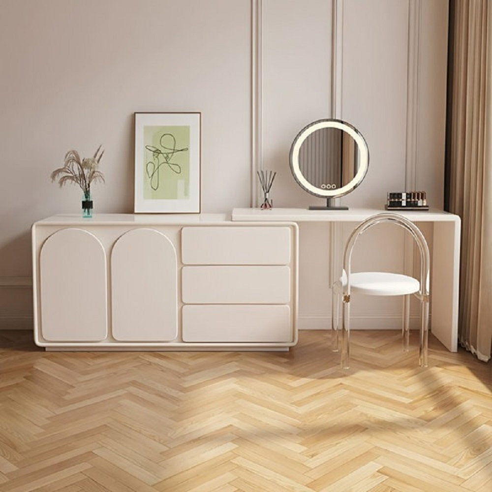 Beige dresser with a round mirror and chair in a room with beige walls and wooden floor.