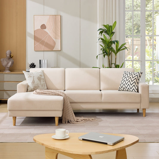 Beige sectional sofa in a living room with a coffee table, laptop, and decorative items.