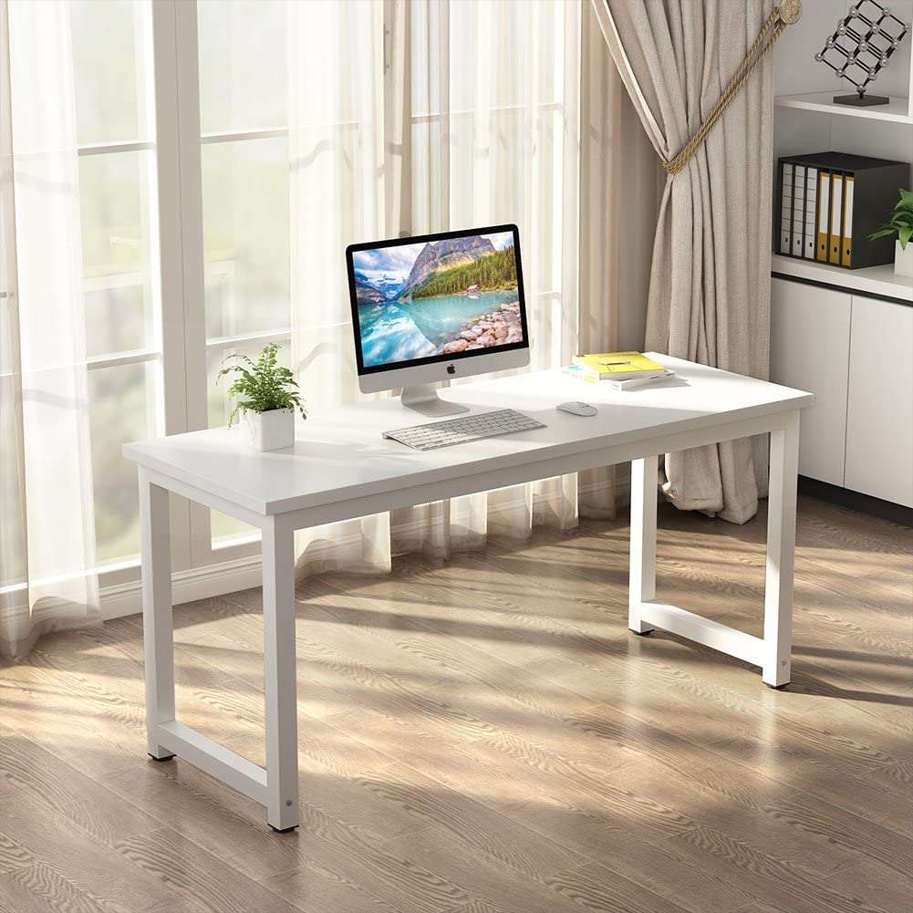 White desk with computer setup in a bright room with curtains