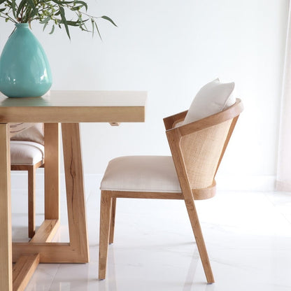 Wooden dining table with chairs and a turquoise vase on a white background