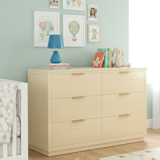 Beige dresser with gold handles in a nursery setting with a lamp, books, and toys.