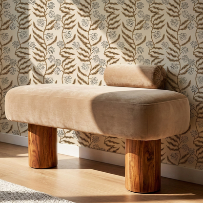 Beige ottoman with wooden legs against a patterned wall.