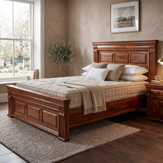 Wooden bed in a bedroom with a large window, plant, and framed picture on the wall.