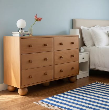 Wooden dresser in a bedroom with a bed and rug
