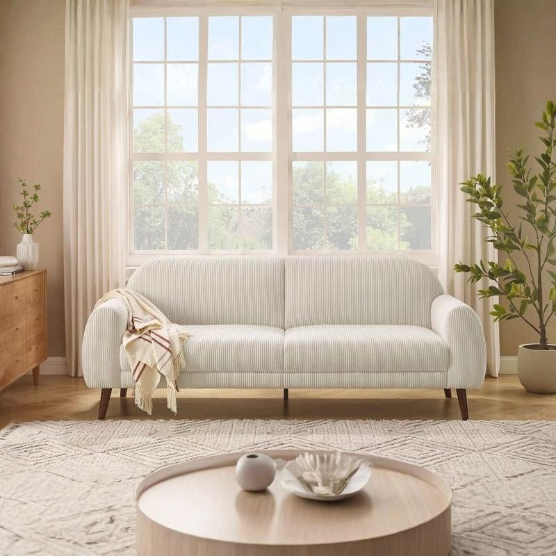 Light gray sofa in a living room with large windows and decorative elements.