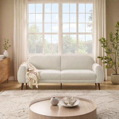 Light gray sofa in a living room with large windows and decorative elements.