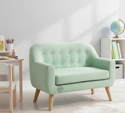Light green children's sofa in a room with a desk and books.